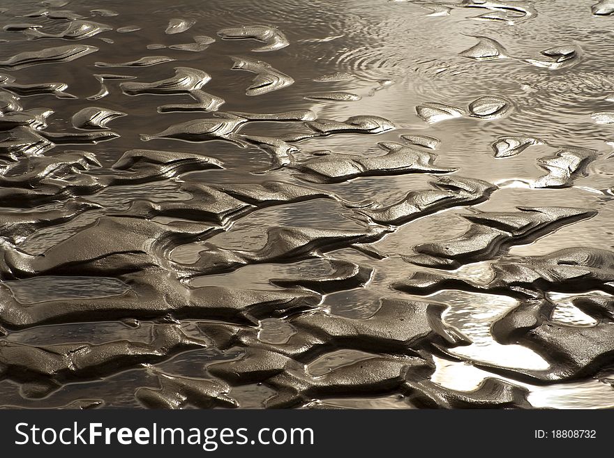 Pools of water form in the patterns of sand on the beach and reflect the late afternoon sun. Pools of water form in the patterns of sand on the beach and reflect the late afternoon sun