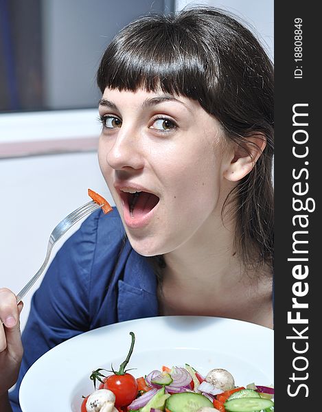 Woman eating vegetable salad in the kitchen. Woman eating vegetable salad in the kitchen