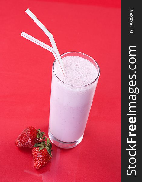 Strawberry milkshake with fresh fruit on red background