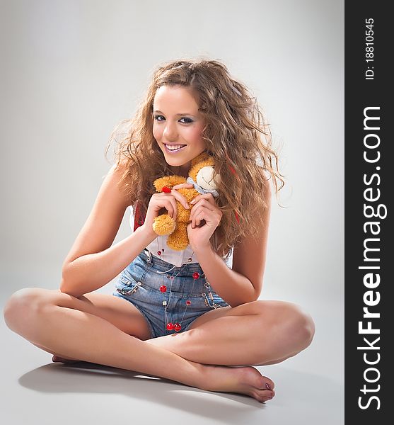 Playful teen girl with teddy on studio neutral background