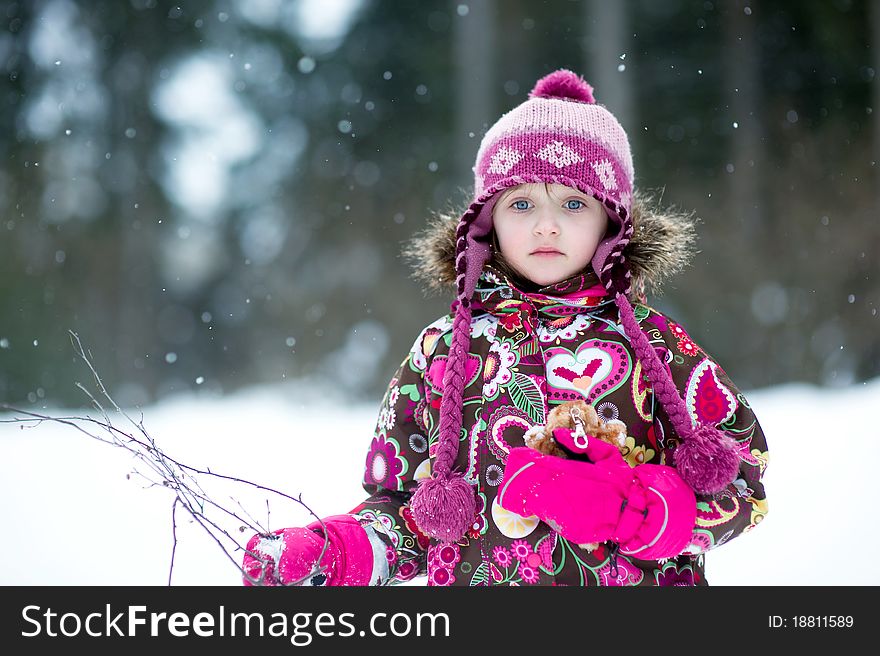 Winter portrait of adorable little girl in colorful pink and brown jacket in the country