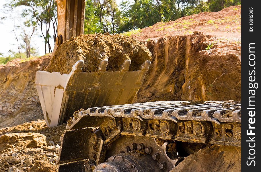 Back hoe standing in mining with raised bucket full of sand