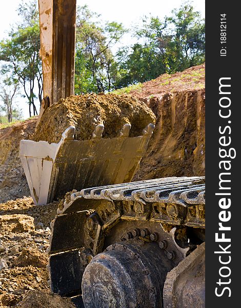 Back hoe standing in mining with raised bucket full of sand