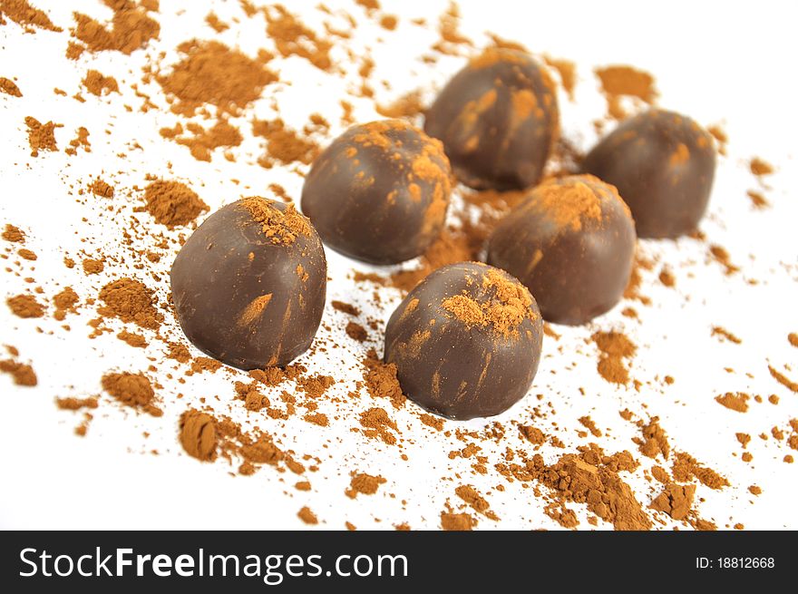 Chocolates sprinkled with cocoa, isolated on a white background