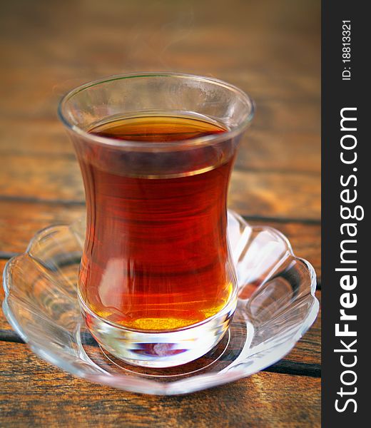 Glass of Turkish tea and saucer on the wooden table. Glass of Turkish tea and saucer on the wooden table