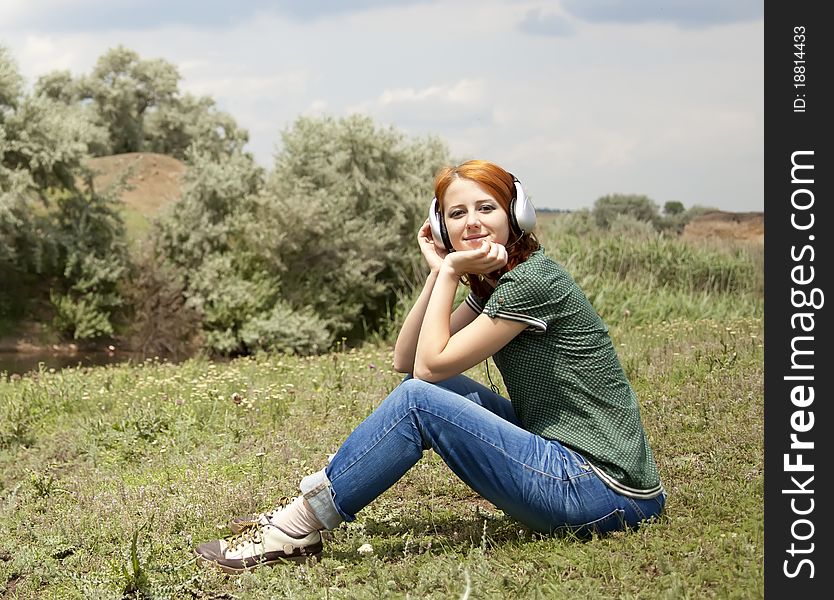 Girl with headphones at grass in spring time.