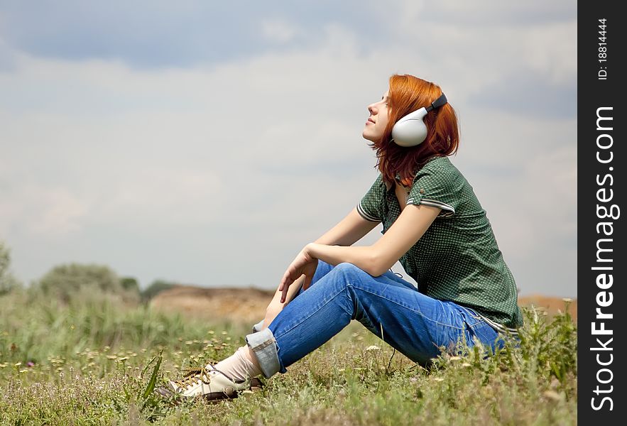 Girl with headphones at grass in spring time.