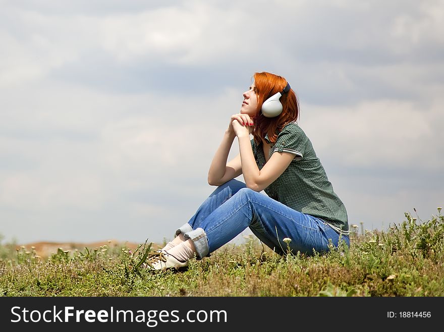 Girl with headphones at grass in spring time.