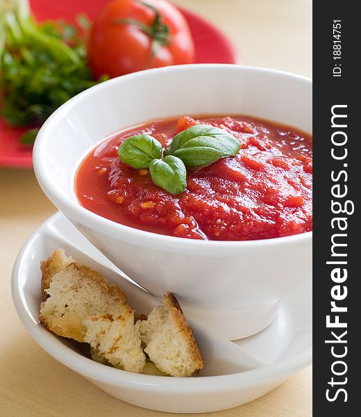 Bowl of tomato soup with bread crouton and basil