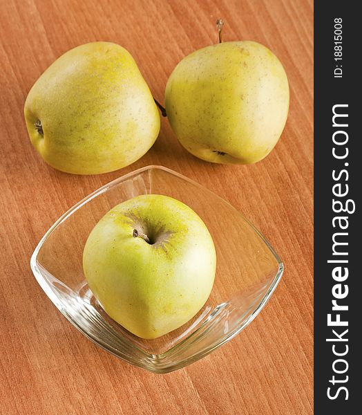 Tree apples in glass boll on a wooden backgtound