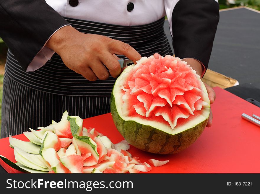 A chef carving flower shapes out of a watermelon. A chef carving flower shapes out of a watermelon