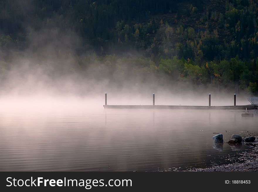 Steam rises on a mountain lake, near a boat dock. Steam rises on a mountain lake, near a boat dock.