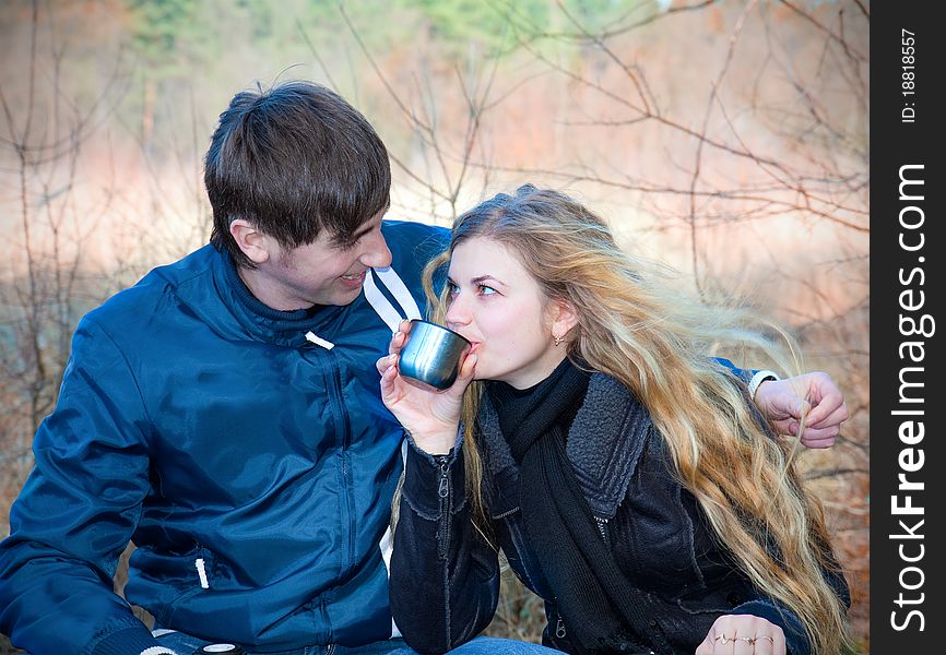 Happy couple drinking tea outside in forest