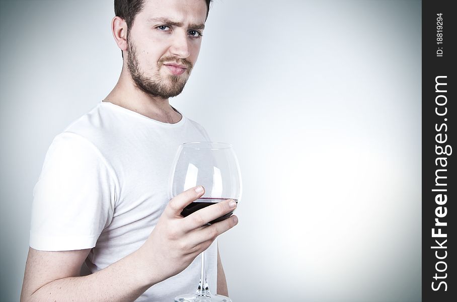 A young man posing with a glass of red wine. A young man posing with a glass of red wine