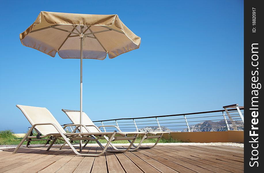 Photo of two deck-chairs with umbrella on the seascape