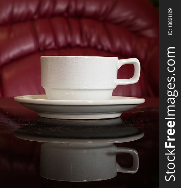 White cup of coffee on Black reflect table and red background