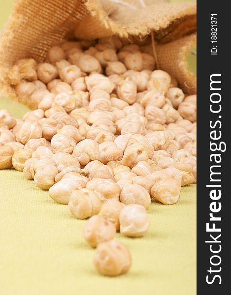 Raw chickpeas spilling out from a jute bag. Studio shot. Selective focus, shallow DOF