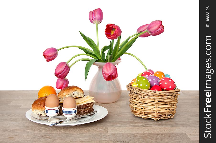 Healthy lunch decorated with tulip flowers and easter eggs om a wooden table isolated over white