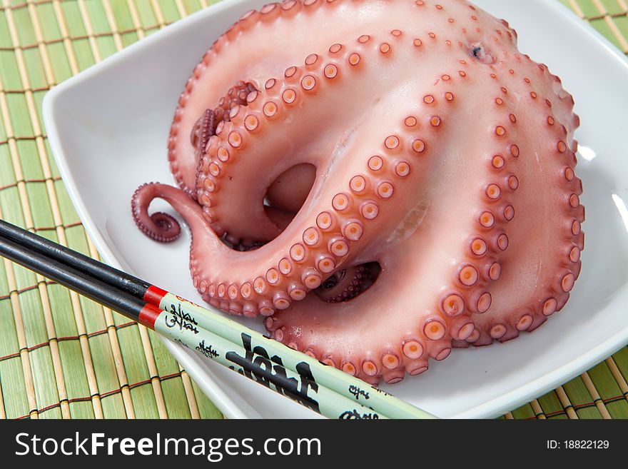 Octopus boiled on white tray and chopsticks