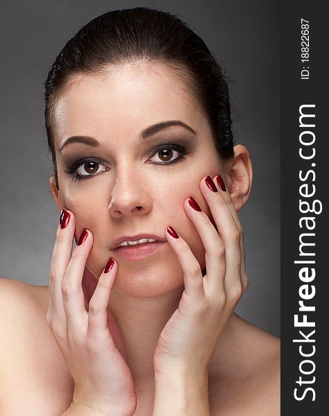 Woman face with red fingernail isolated on gray