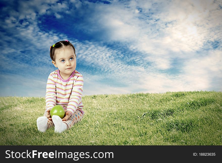 The child with an apple against a green meadow