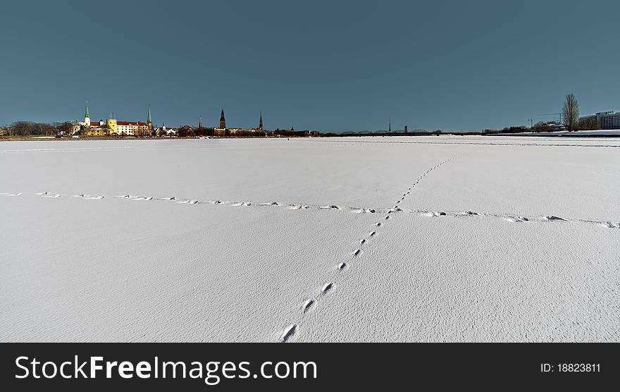 Footprints on the snow over the frozen river in the city Riga.