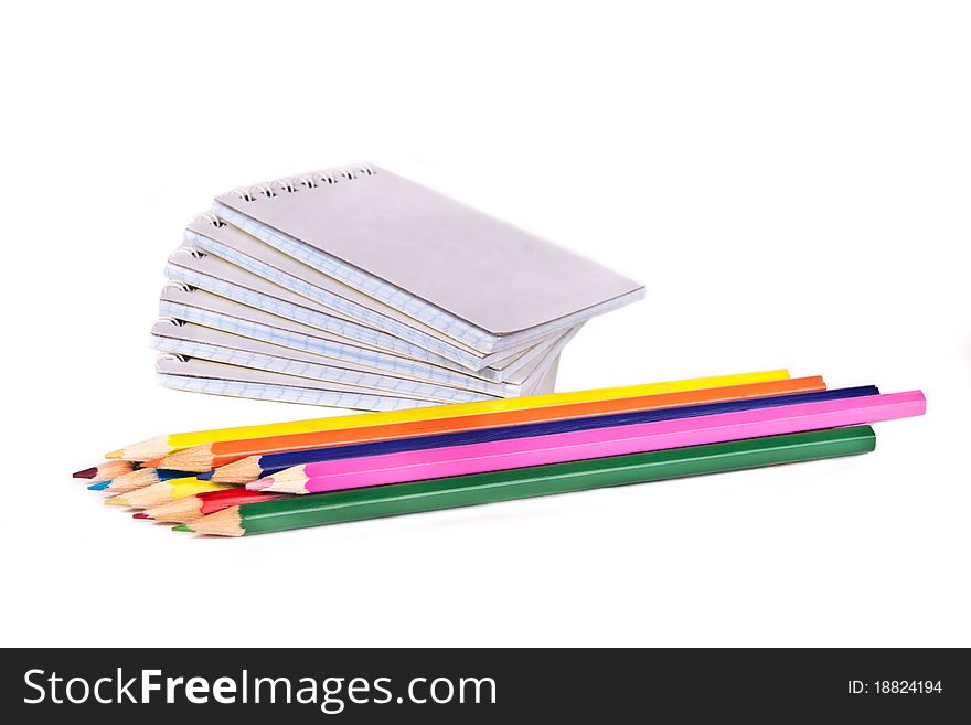 Colored pencils and a pile of notepads. Colored pencils and a pile of notepads