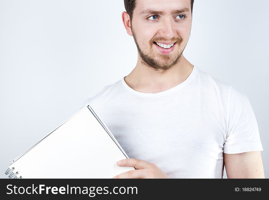 Isolated image of a young blonde man holding a notebook and smiling happily. Isolated image of a young blonde man holding a notebook and smiling happily