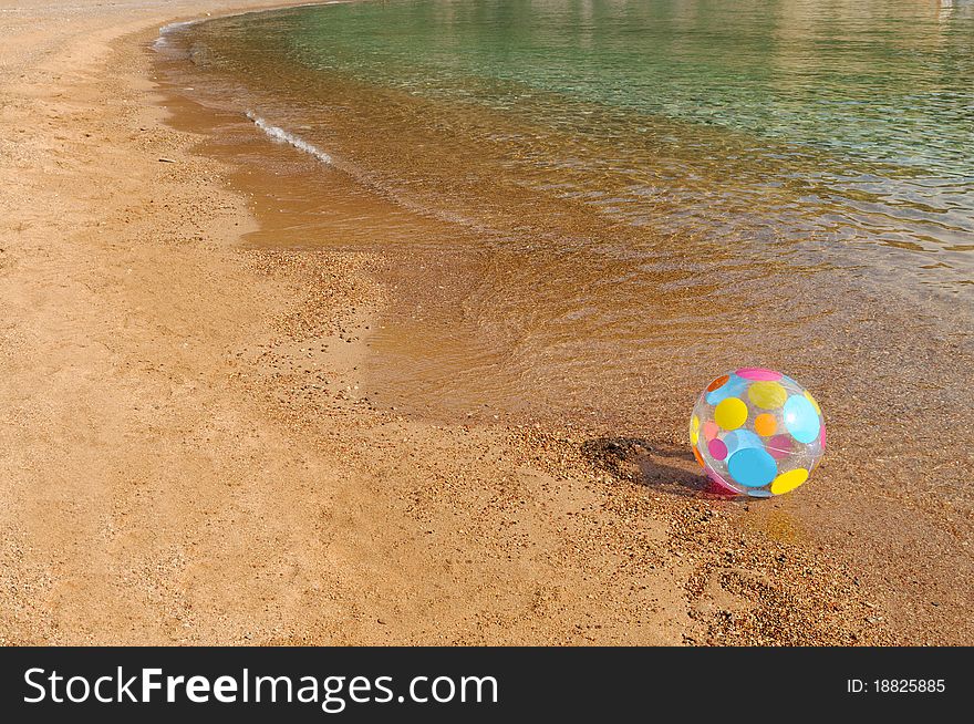 Multicolored ball on the huge sandy beach, ideal for summer designs. Multicolored ball on the huge sandy beach, ideal for summer designs