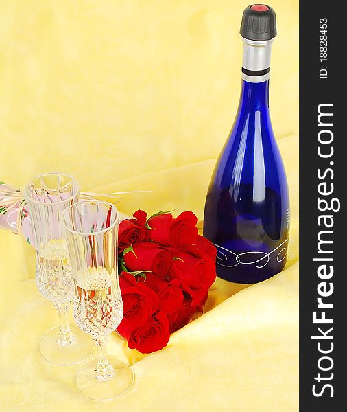 Champagne and roses for celebration of Valentines day with blue bottle on yellow background