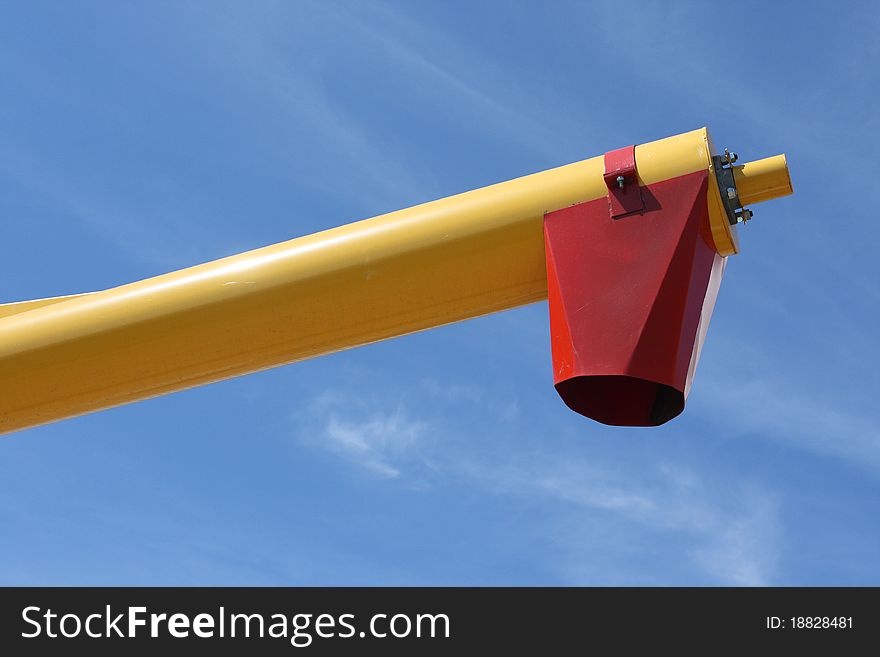 Red and yellow auger for moving grain from trucks to place of storage.