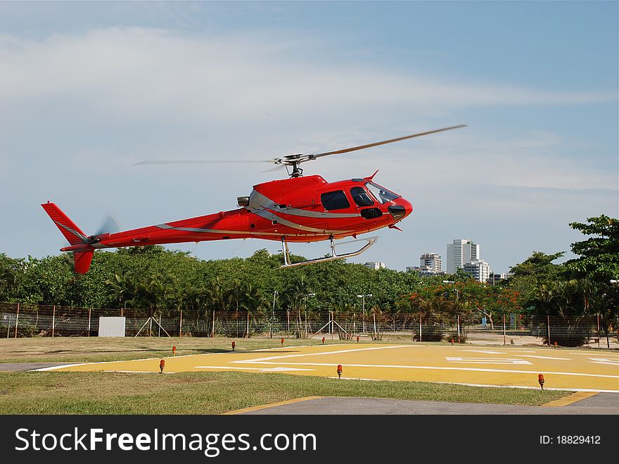 Red helicopter landing on heliport