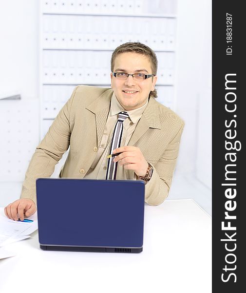 Portrait of businessman using desktop computer, looking at camera