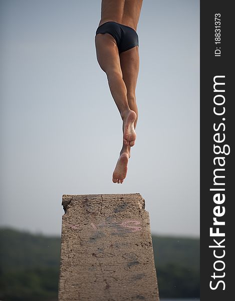 Man jumping from diving platform into lake