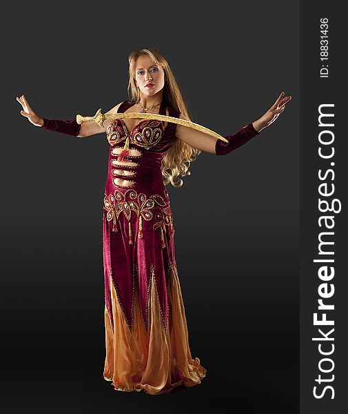 Beauty blond arabian dancer stand with saber on breast