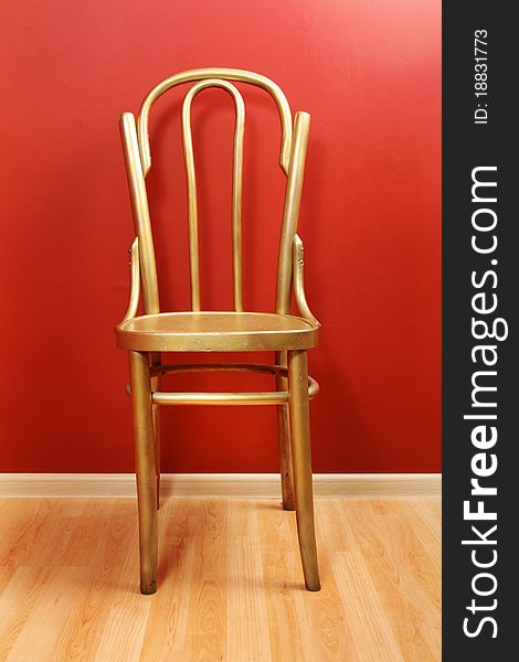 Old-fashioned golden wood chair against red wall