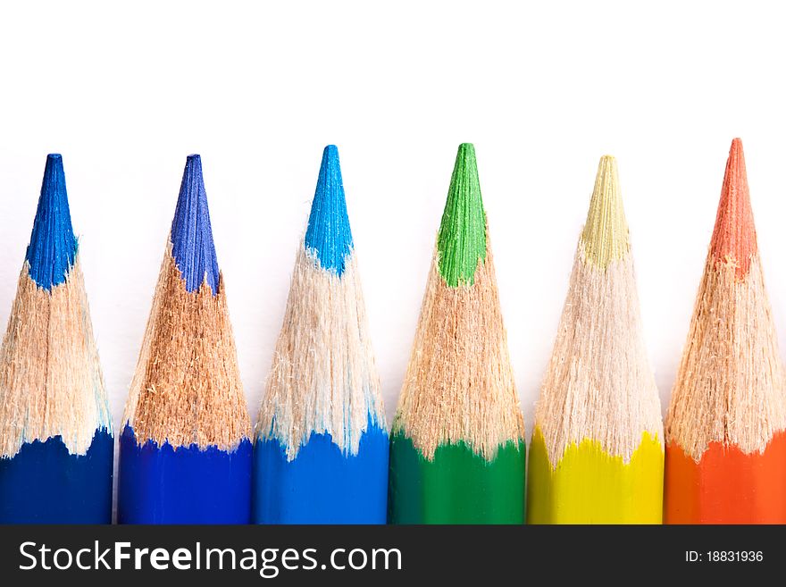 Six colored pencils across white