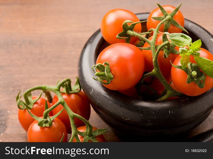 Photo of tomatoes inside a black mortar ready to be smashed for preparing tomatoe sauce