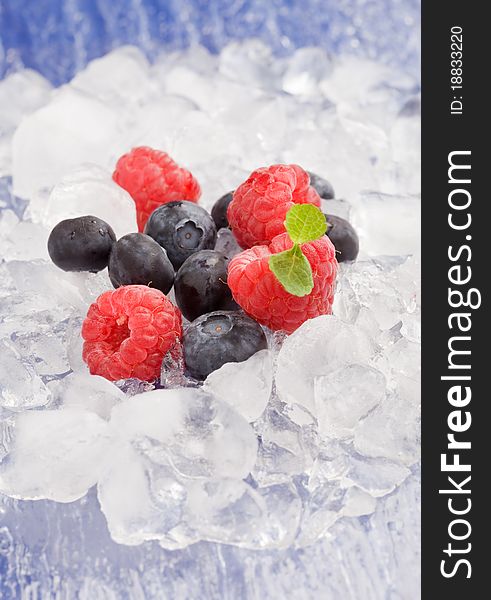 Photo of raspberries and blueberries on ice with mint leaves