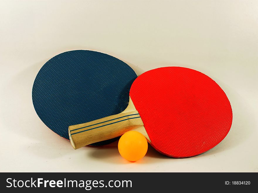 Red and blue ping pong paddles with a yellow ball