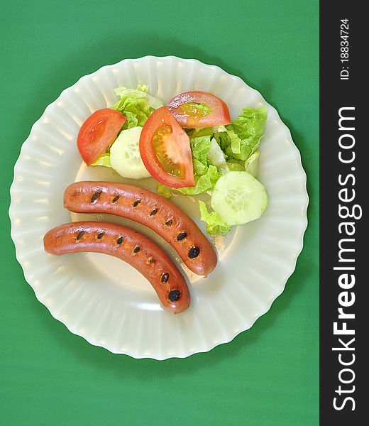 Plate of sausages and lettuce and tomato salad. Plate of sausages and lettuce and tomato salad