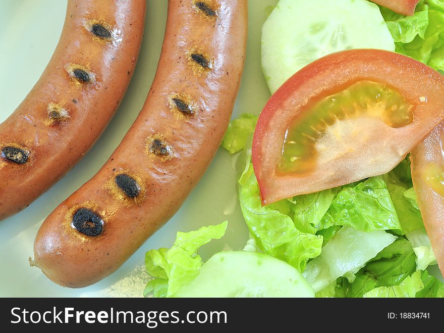 Plate of sausages and lettuce and tomato salad. Plate of sausages and lettuce and tomato salad