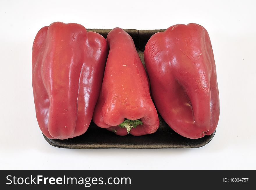 Three red peppers in supermarket tray