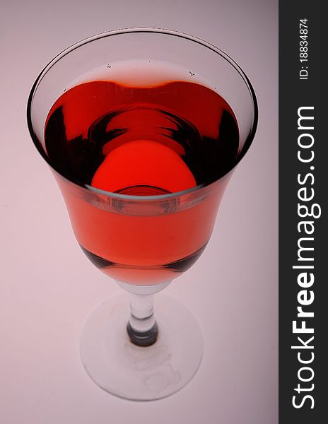 A cool glass of rose wine against a gray backdrop lit from below.