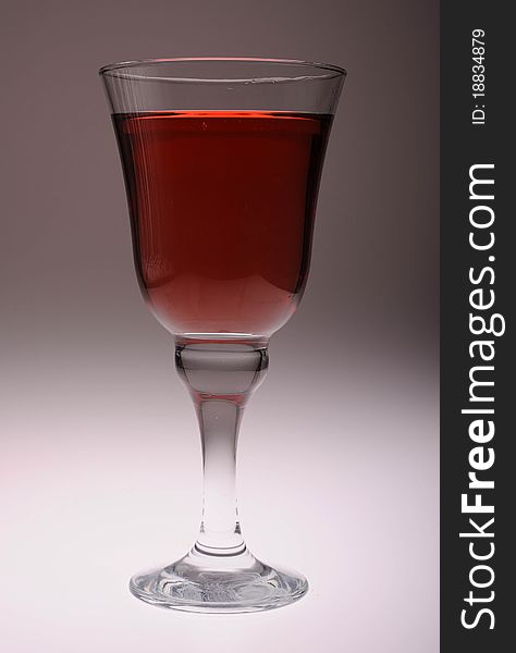 A cool glass of rose wine against a contoured gray backdrop lit from below.
