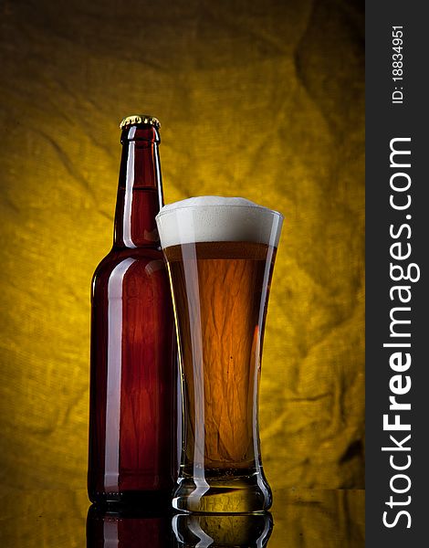 Beer in glass with bottle on yellow background