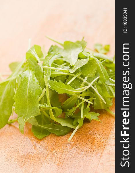 Photo of delicious rocket salad on wooden cutting board