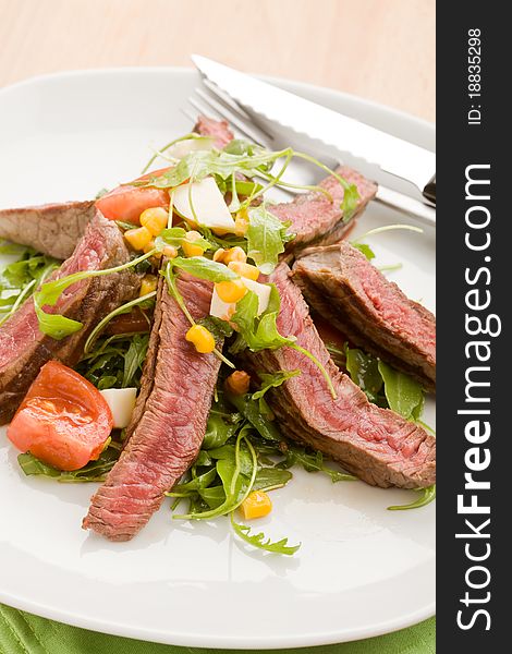 Delicious slices of meat with rocket salad and toamtoes