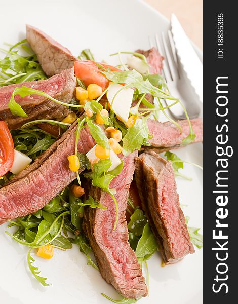 Delicious slices of meat with rocket salad and toamtoes