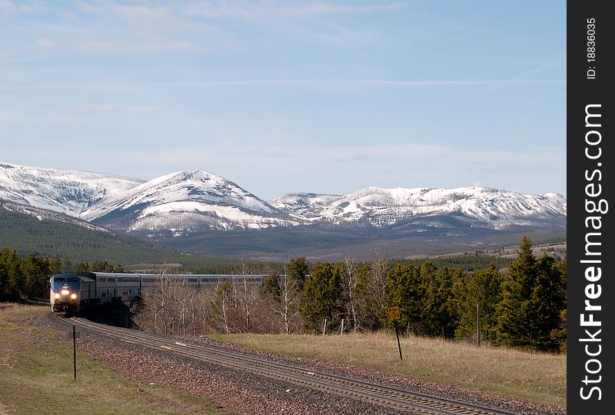 This image of the passenger train coming around the bend in the tracks with the snowcapped mountains in the background was taken in NW Montana.